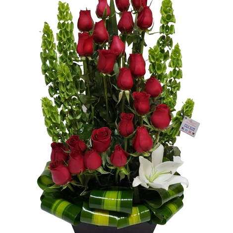 Arreglo de rosas rojas compuesto por 24 piezas en forma escalonada y follaje fino colocadas en una base rectangular
